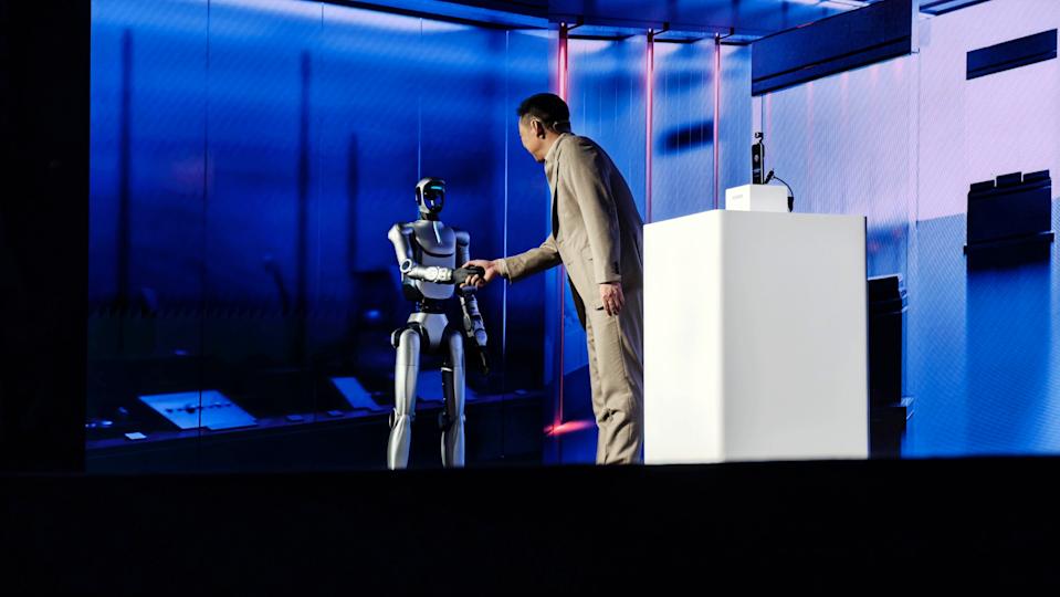 Honor's humanoid robot is shown shaking hands with CEO James Li on stage at MWC
