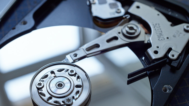 Close-up of an opened hard disk drive showing the reflective platter and mechanical actuator arm.